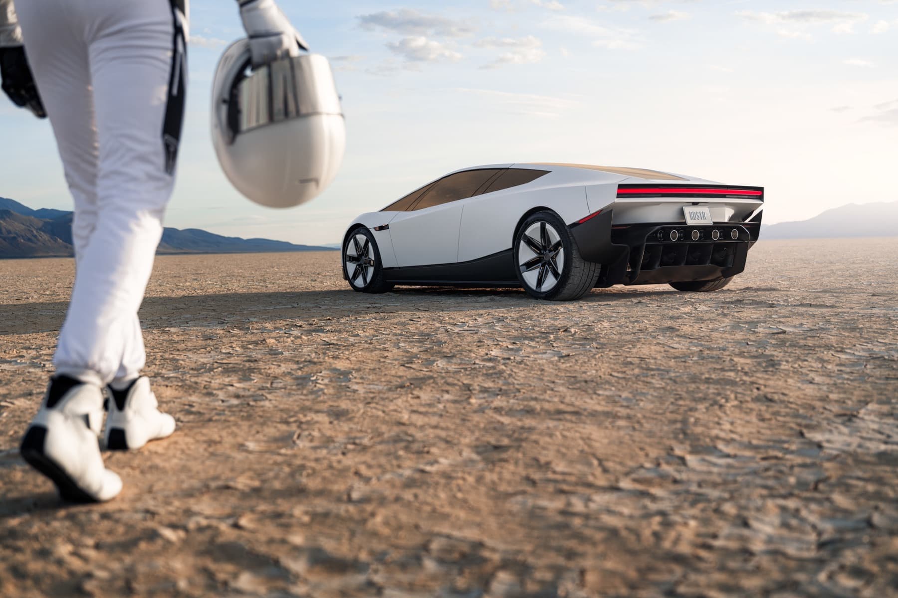 White Tesla Roadster parked in the desert with a space-suited figure in the foreground.