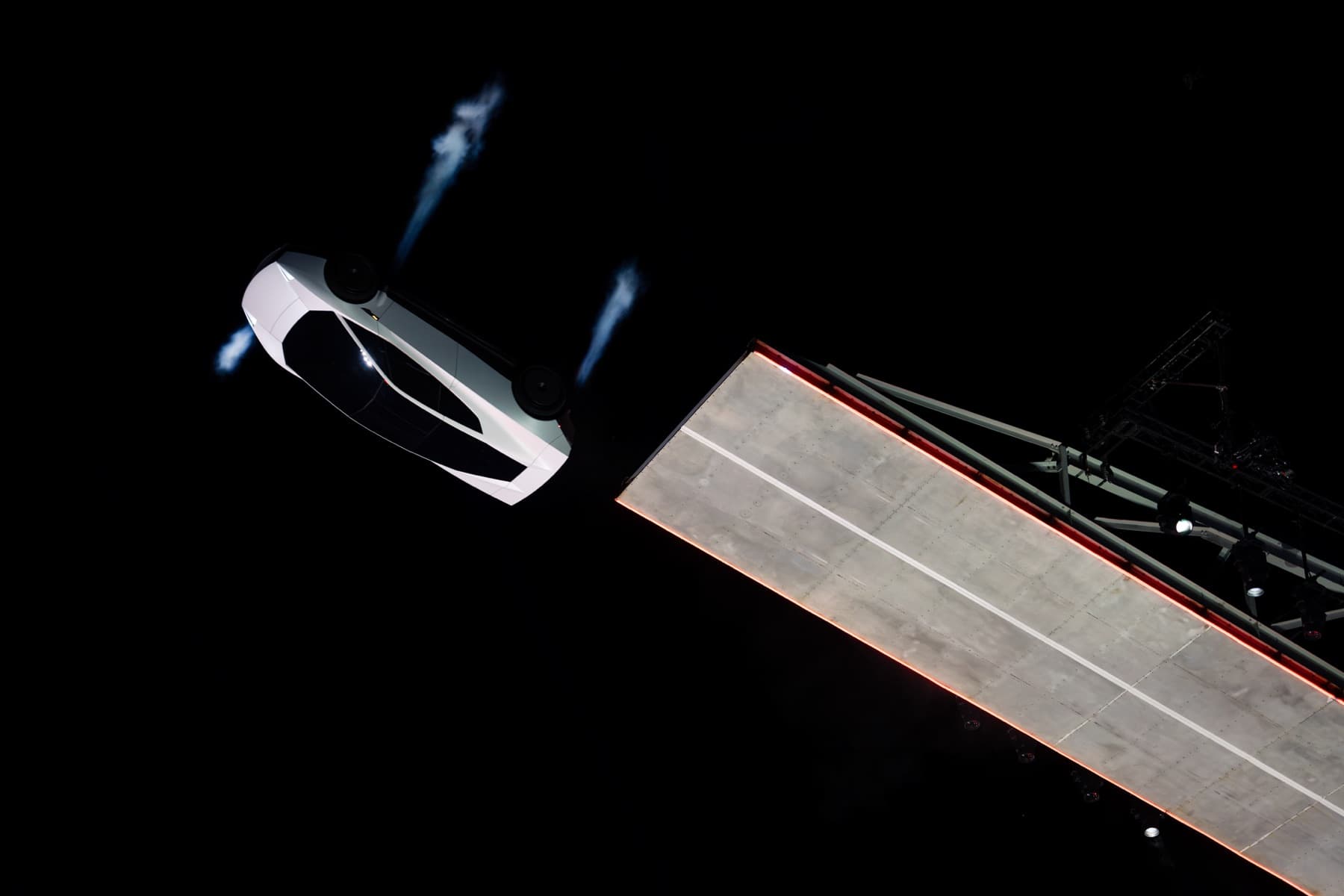 Roadster rotating in the air beside the end of the ramp with gas plumes visible.