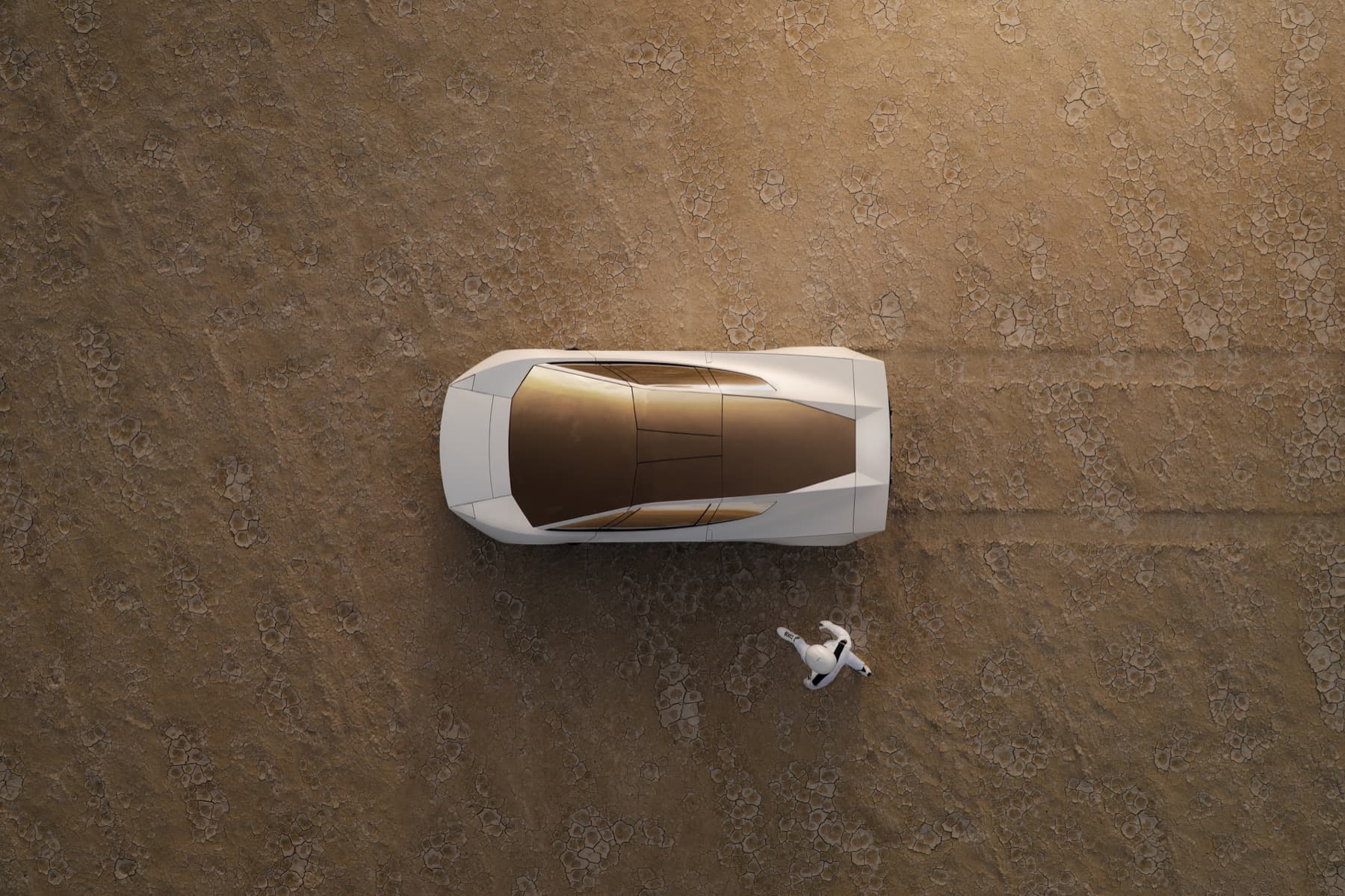 Overhead photograph of the white Roadster on cracked desert ground.